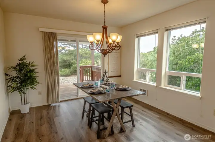 Spacious dining room with luxury vinyl plank flooring. Sliding glass door leads to covered back deck and backyard