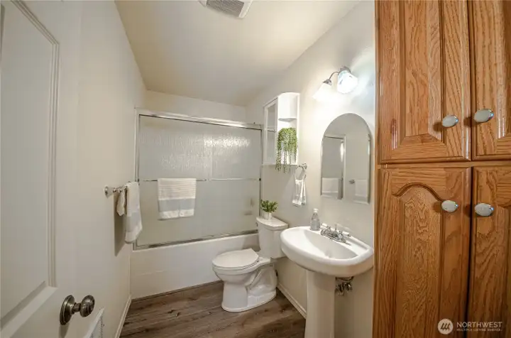 Main full bath with pedestal sink, sliding shower door and linen closet