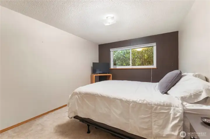 Primary bedroom with window facing backyard. Greenery provides a sense of seclusion.