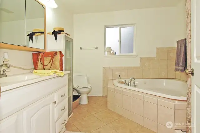 Primary bathroom on upper level with large corner soaking tub and separate shower around the corner
