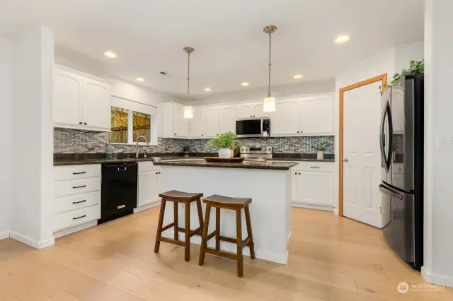 Updated kitchen with canned lights, painted cabinets and pretty pendants over island.