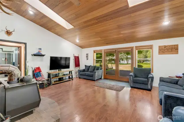 LVP flooring throughout the house, central wood stove, vaulted cedar lined ceiling with two skylights, french doors to large deck and patio.
