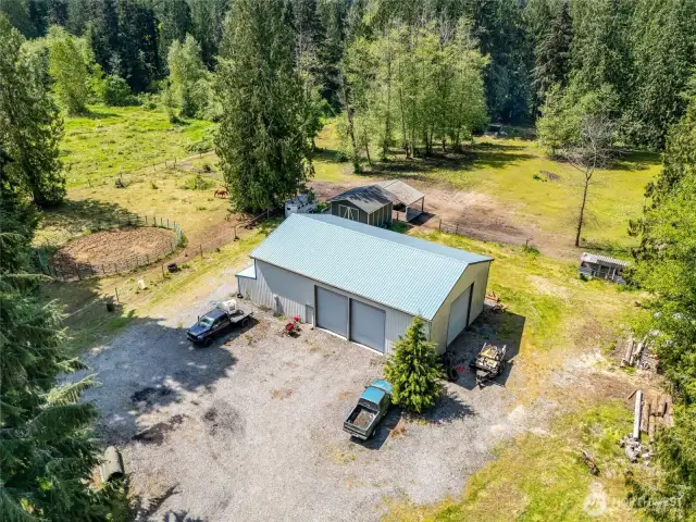 View of 40 x 60 shop with 36x40 loft with exterior entrance. Four 18' doors for drive through capabilities.  Hay barn, 3 stall loafing shed, 60' round pen, chicken coop, Shop has an a air compressor, mini split for heat/AC in the loft, stack washer and dryer, hot water heater, meat locker, refrigerator, freezer. Multiple pastures with gates. Easy parking and turn around capacity.