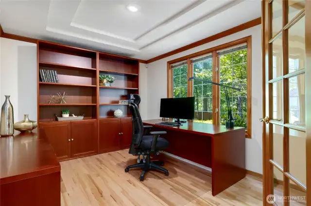 Sun-drenched office with custom built-ins, tray ceiling and oversized windows overlook the front of the home, creating a bright and inspiring space for remote work or study. French doors add elegance and privacy.