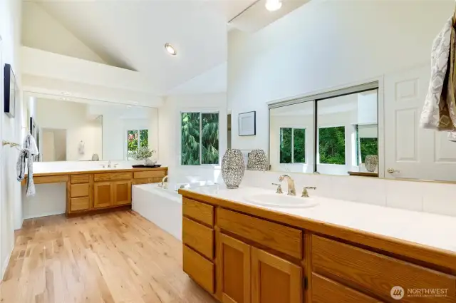 Expansive en-suite bath with vaulted ceilings, dual vanities, soaking tub, a separate room with a toilet and a walk in closet.