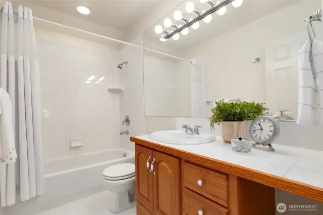 Located directly next to the first bedroom this bright and clean full bathroom features a tile shower/tub combo, large vanity with ample counter space, and a wide mirror with modern lighting. Perfectly situated for guest or family use.
