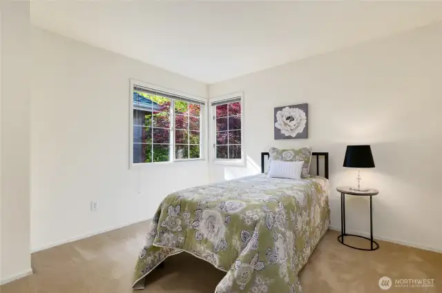 The second of four bedrooms is bright and cheerful with large corner windows. Neutral tones, soft carpet, and natural light make this a comfortable and inviting space for guests or family.
