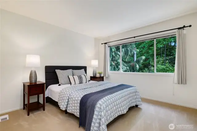 The fourth bedroom with windows framing peaceful evergreen views. Soft natural light fills the room, creating a serene and restful atmosphere.