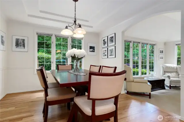 Sophisticated formal dining room with tray ceiling, and hard wood floors. An arched entry connects seamlessly to the formal living room, creating an elegant space for entertaining and gatherings.