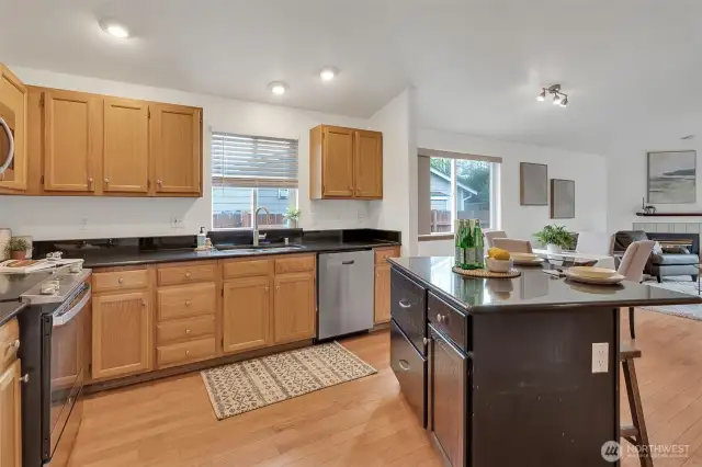 The open-concept layout flows seamlessly into the kitchen featuring granite counters, an island with breakfast bar.