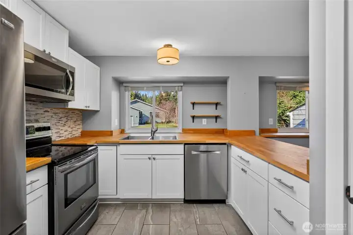 Kitchen boasts stainless steel appliances and butcher block countertops.