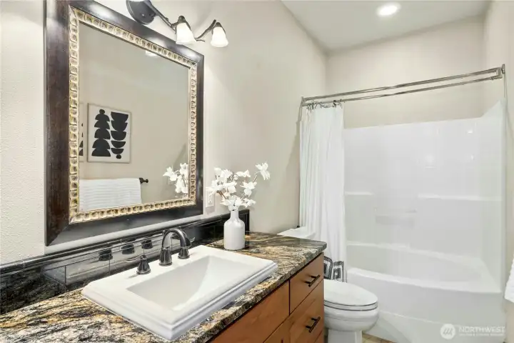 The shared upper level full bathroom features a granite vanity and shower/tub combo.