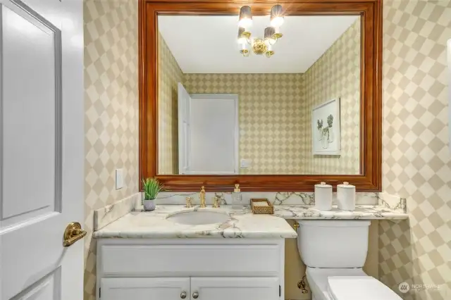 Guest bath is inviting with charming wallpaper and marble vanity.