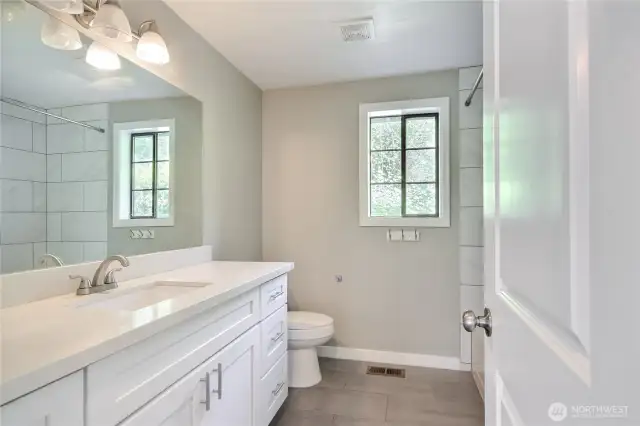 Full bath on main floor lacks no luster. Same lovely tile, quartz and white shaker cabinets.