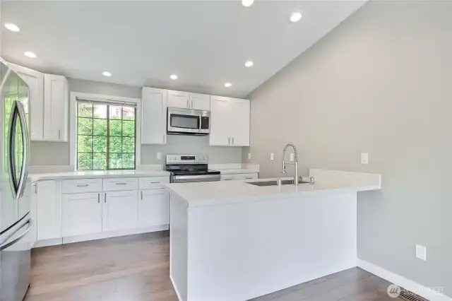 Updated kitchen has white shaker cabinets, quartz counters, under-mount sink and all stainless-steel appliances.