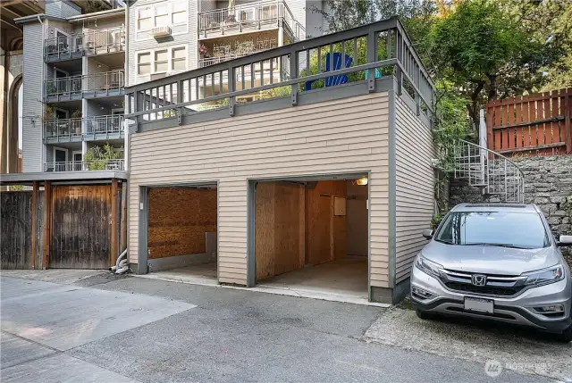2 separate garage bays with individual keypads. Additional uncovered parking spot to the right. Spiral staircase leads to rear patio and backyard pond.