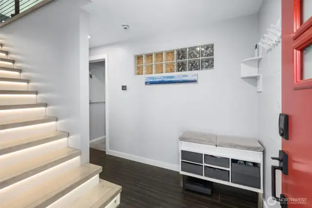 A sleek LED-lit staircase welcomes you at the door, leading upstairs to a bright, modern living room.