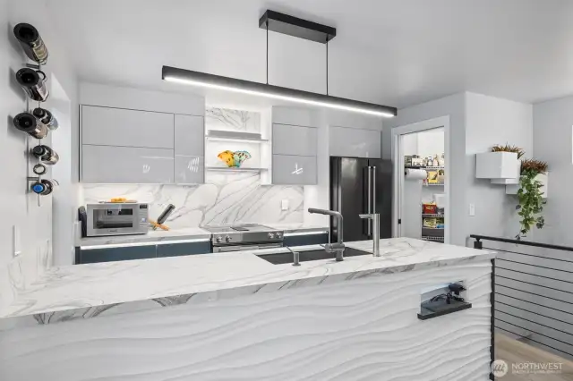 This modern kitchen boasts custom cabinets, high-end countertops, premium appliances, and a sleek backsplash, where style meets function.