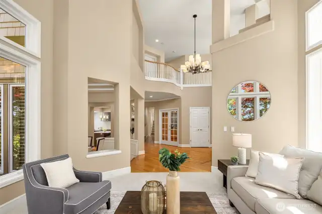 Vaulted ceilings are a key architectural feature of the home. Tall windows flood the space with natural light, open architectural niches allow for easy flow between and sightlines between living and dining rooms.