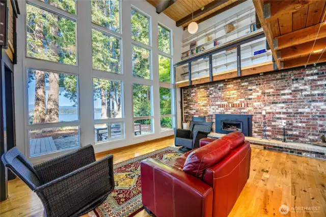Living room features solid brick wall with fireplace and wood box that can be loaded from outside.