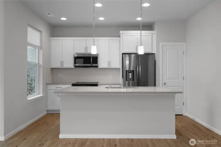 Modern kitchen featuring stone countertops, stainless steel appliances, and a large island with seating.