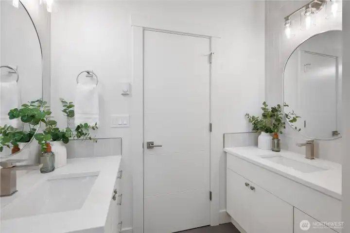 Two vanities, two sinks, tile floor, quartz counters.