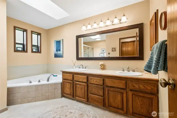 Primary bath with soaking tub, double vanity, tiled floor, newer mirror and LOADS of storage! Primary bath with soaking tub, double vanity, tiled floor, newer mirror and LOADS of storage!