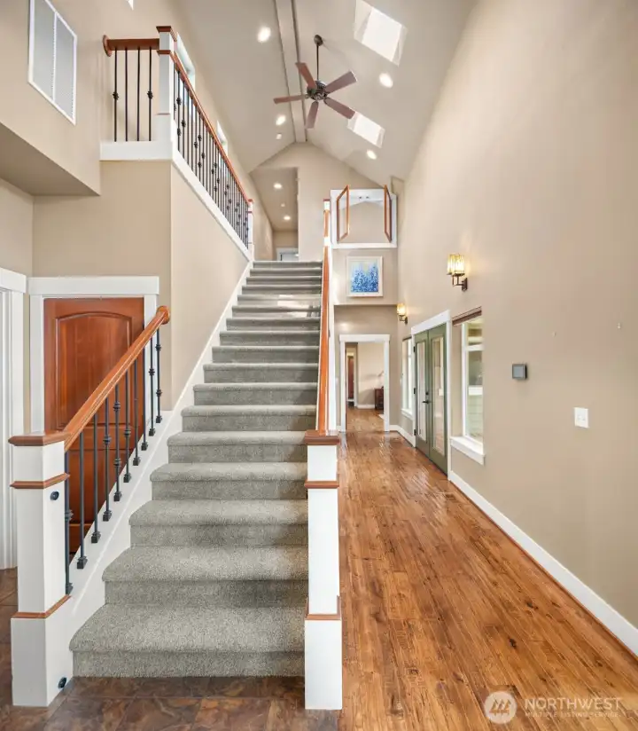 Powder room located to the left of the staircase. Down the hallway and to the right are french-doors to the back covered deck. Further down the hallway you'll find the primary bedroom, laundry room, and garage entry.