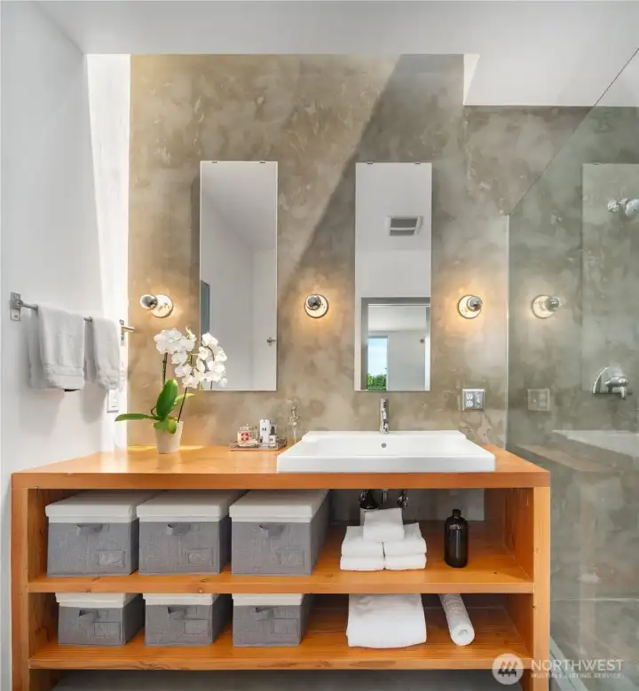 The primary bath features a custom reclaimed fir vanity, hand-finished milestone walls and floors, and a skylight.