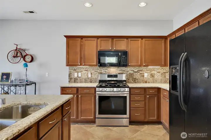 Spacious kitchen and dining area featuring newer granite countertops, under-cabinet lighting, stainless steel appliances, a center island, and seamless access to outdoor living.
