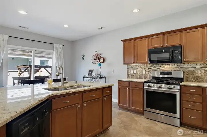 Spacious kitchen and dining area featuring newer granite countertops, under-cabinet lighting, stainless steel appliances, a center island, and seamless access to outdoor living.