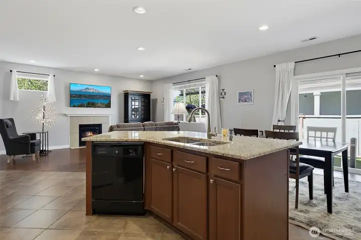 Spacious kitchen and dining area featuring newer granite countertops, under-cabinet lighting, stainless steel appliances, a center island, and seamless access to outdoor living.