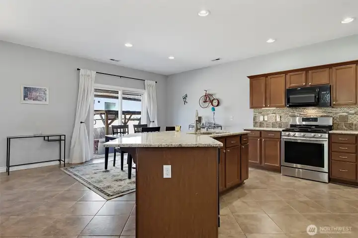 Spacious kitchen and dining area featuring newer granite countertops, under-cabinet lighting, stainless steel appliances, a center island, and seamless access to outdoor living.