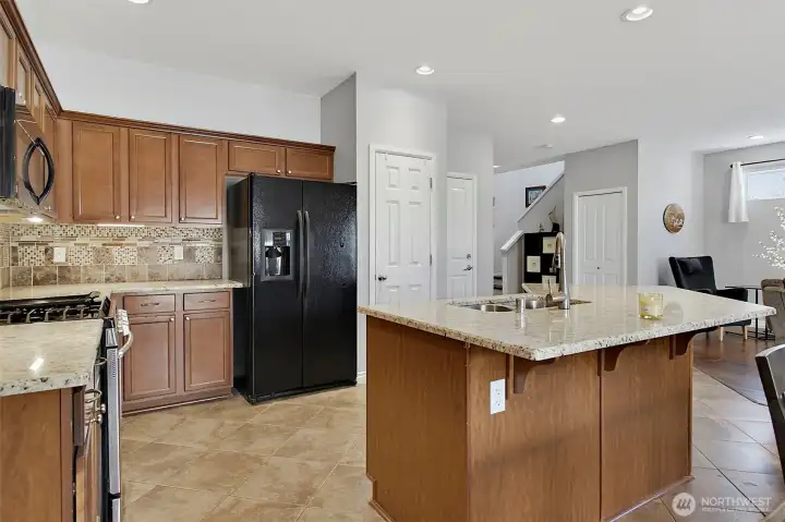 Spacious kitchen and dining area featuring newer granite countertops, under-cabinet lighting, stainless steel appliances, a center island, and seamless access to outdoor living.
