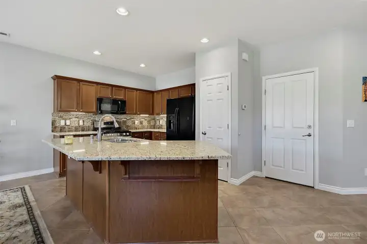 Spacious kitchen and dining area featuring newer granite countertops, under-cabinet lighting, stainless steel appliances, a center island, and seamless access to outdoor living.