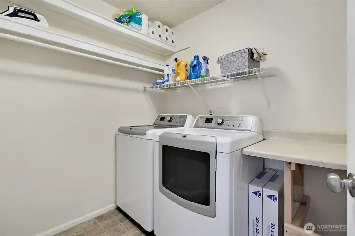 Convenient upstairs utility room with built-in shelving, folding counter, and additional storage space for everyday functionality and organization.