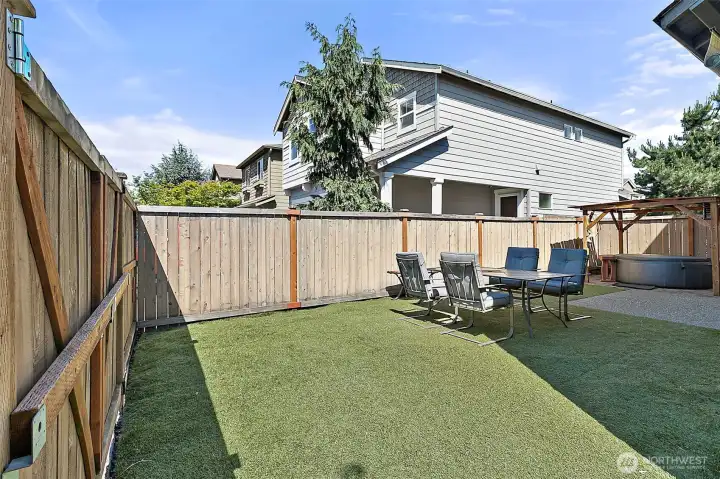 Low-maintenance backyard designed for relaxation and entertaining, featuring astro turf, hot tub, outdoor seating area, storage shed, and plenty of space to enjoy outdoor living with minimal upkeep.