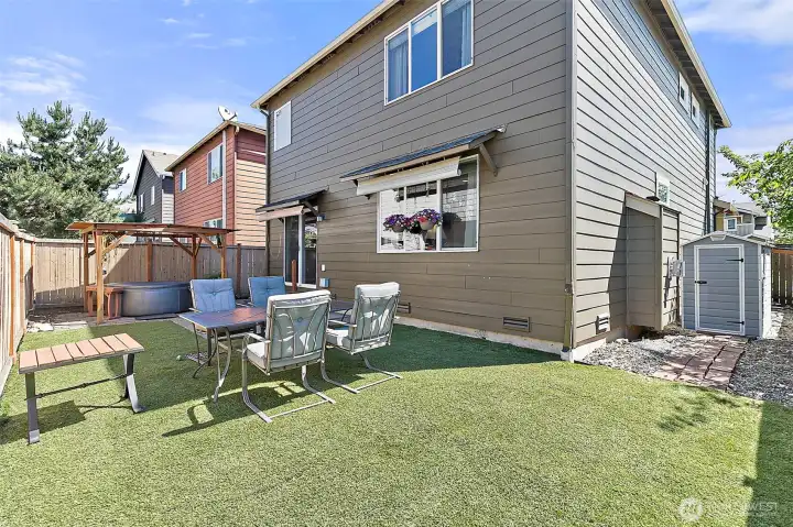 Low-maintenance backyard designed for relaxation and entertaining, featuring astro turf, hot tub, outdoor seating area, storage shed, and plenty of space to enjoy outdoor living with minimal upkeep.