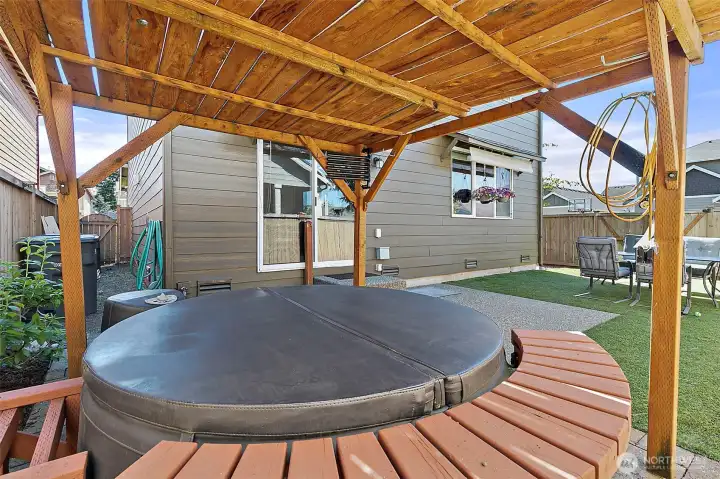 Private backyard retreat featuring a relaxing hot tub, covered pergola, paver patio, and low-maintenance outdoor space designed for year-round enjoyment and entertaining.