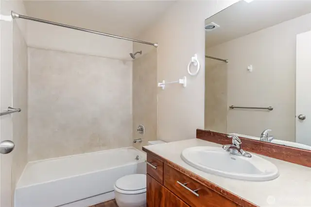 Centrally located full bath with sleek countertops and warm cabinetry.