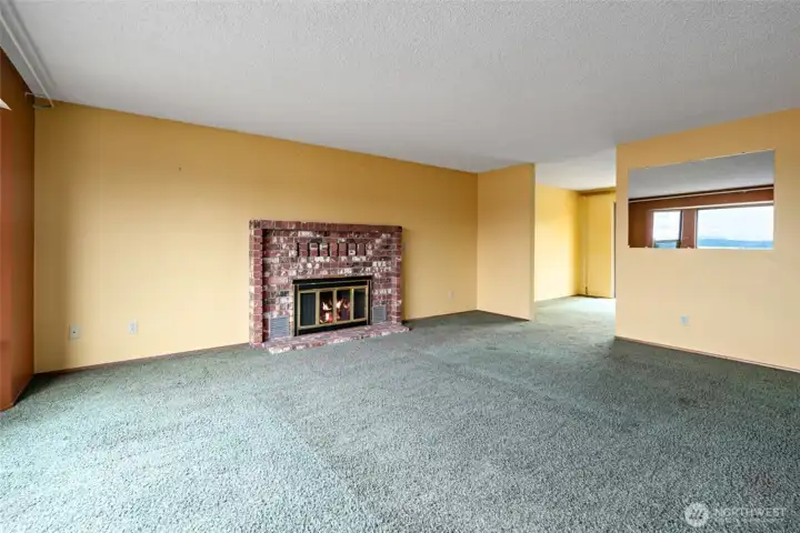 Spacious living room with wood burning fireplace . To the right is the dining room .