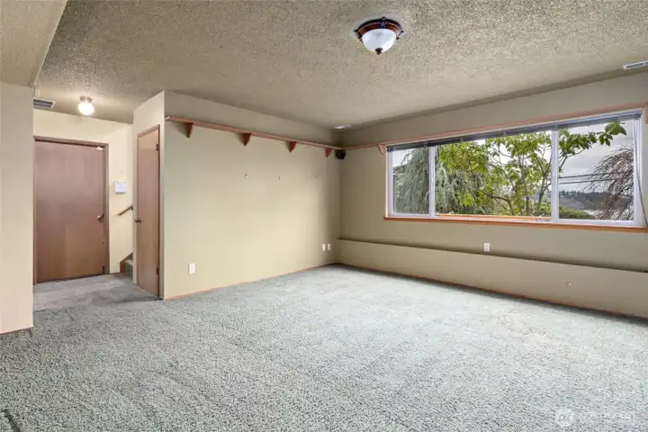 A view of the Family room looking at garage door entrance.  Closet to the right has space under the stairs. Note water view from this room as well.
