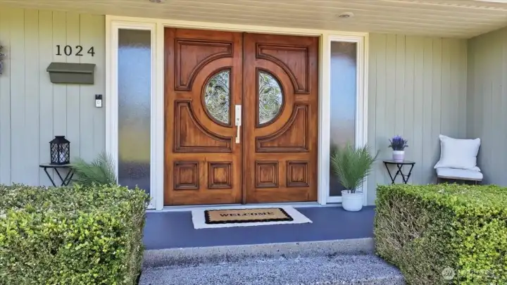 Elegant covered front porch with custom wood double doors and welcoming entry.