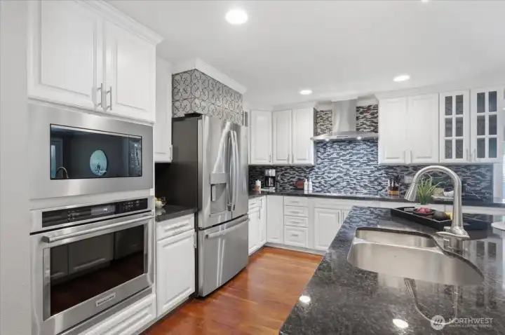 Open concept gourmet kitchen with stainless steel appliances, custom tile backsplash, and ample cabinet storage.