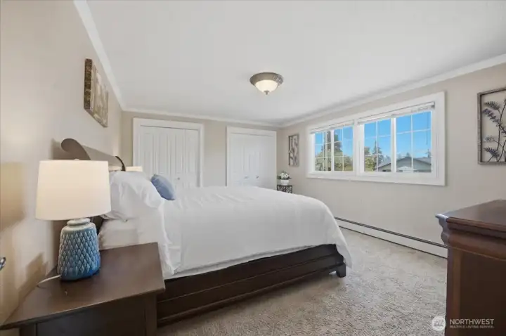 Spacious primary bedroom with large windows and peaceful backyard views.