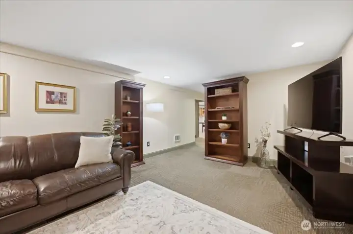 Expansive lower-level living room with built-in shelving and versatile living space.