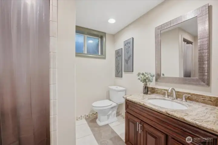 Updated lower-level bathroom with granite vanity and modern finishes.