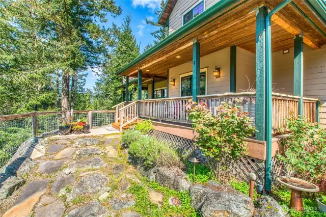 Welcome home. This photo showcases the front entrance and covered deck that wraps around the home.