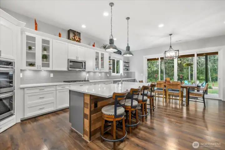 Barnwood decor on massive island and the huge sliding doors to the back are just a few of the details the home offers. Beautifully detailed hanging lights over the island offer the perfect ambiance.