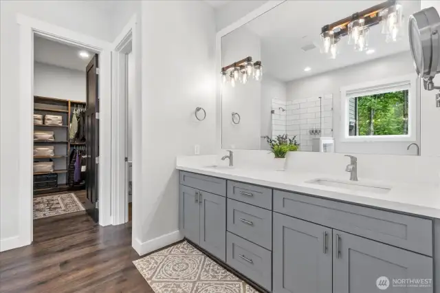 5 piece primary bath with quartz throughout, double sinks, separate toilet area leading to custom shelving in massive walk in closet.